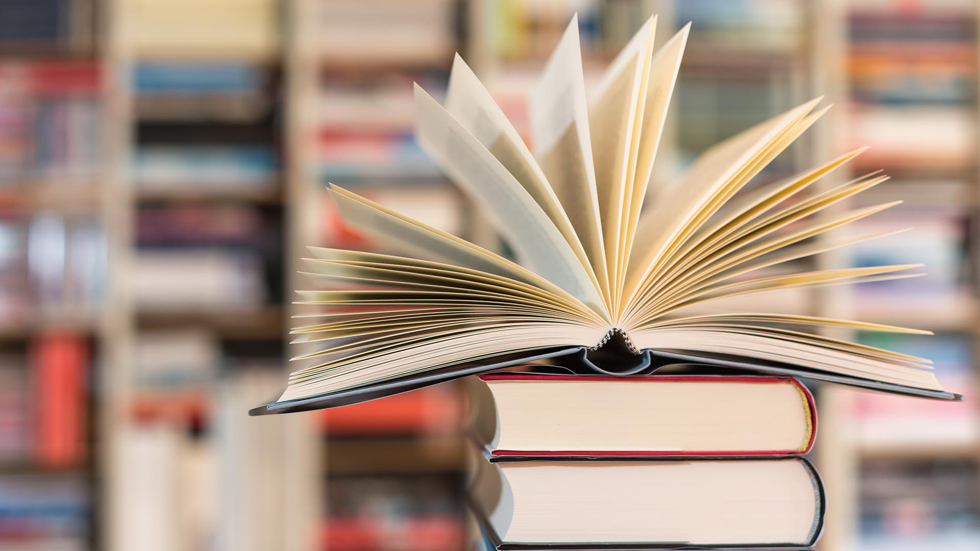 Bücherstapel und oben drauf ein aufgeschlagenes Buch